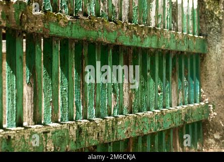 Old grunge vintage weathered wooden faded pale cracked painted green boards house garden fence close Stock Photo