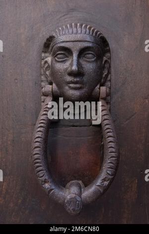 Vintage egyptian pharaoh face door knocker on a wooden door. Stock Photo