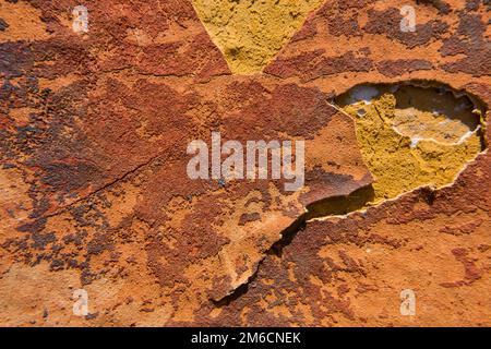 Cracked orange paint on a yellow concrete wall texture. Stock Photo
