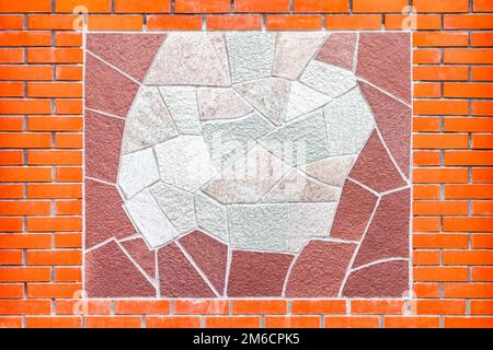 Ornament of decorative different tiles on a wall of red brick. Stock Photo
