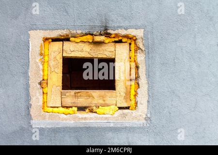 A square hole with wooden blocks in a brick wall painted with gray paint. Stock Photo