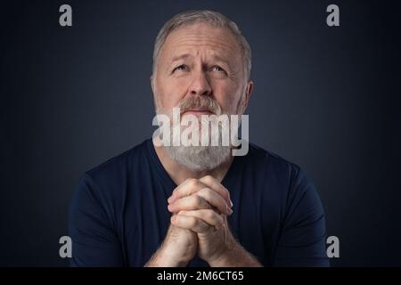 Senior with beard praying Stock Photo