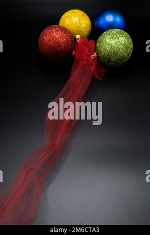 Vertical view of red, yellow, blue and green christmas balls with red fabric. Stock Photo