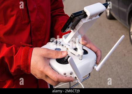 Man operating of flying drone. Drone remote control in man hands. Stock Photo