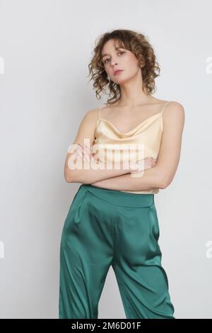 Female model wearing green and beige silk outfit, camisole top and trousers. Classic and simple summer fashion. Studio shot. Stock Photo