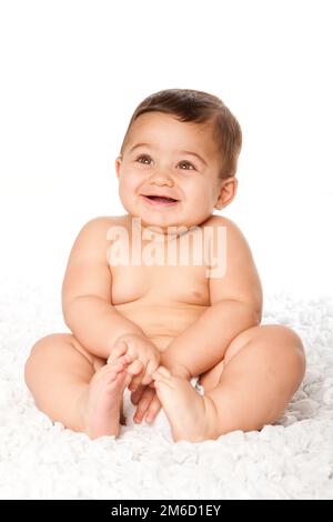 Cute baby infant with big eyes sitting wearing diaper Stock Photo