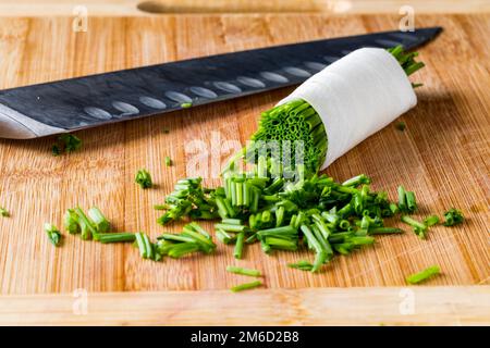 Freshly chopped chives on a cutting board with a sharp knife. Stock Photo