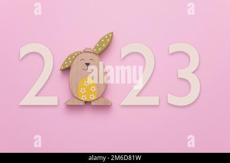 In celebration of Easter or the Chinese New Year 2023, the year of the Rabbit. A wooden rabbit on a pink background displaying the number 2023. Stock Photo