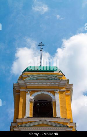 Yellow Orthodox Christian church with a green dome in summer against a blue sky with white clouds. Stock Photo