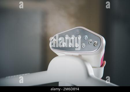 Close up of electric hand steam generator while it's hot on the ironing board place for clothes Stock Photo