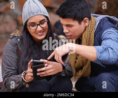 College connections. a young man pointing to something on his girlfriends phone. Stock Photo