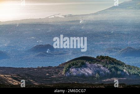 Aerial view of Catania metropolitan area with city center and port, smoking craters and landscape seen from Mount Etna volcano, in winter Stock Photo