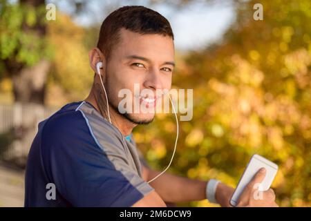 Young latin man listening to music runner running jogging autumn fall Stock Photo