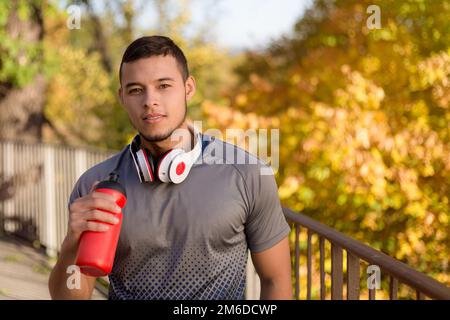 Young latin man drinking water runner running jogging autumn fall copyspace copy space Stock Photo