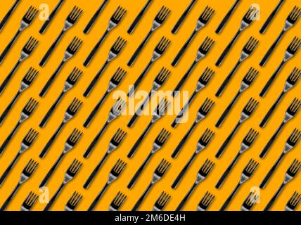 Many black plastic forks on yellow background, top view Stock Photo