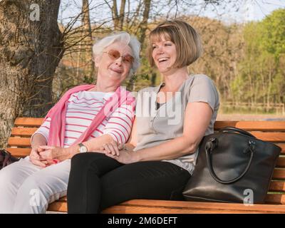 Senior lady an daughter smiling while sitting in the park Stock Photo
