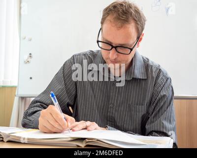 A man writing up paperwork at work. Stock Photo