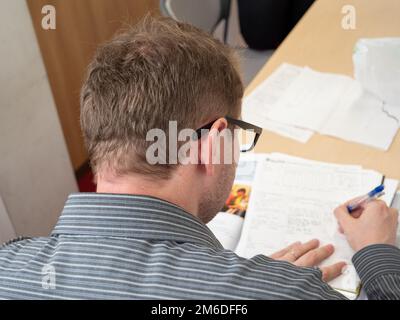 A man writing up paperwork at work. Stock Photo