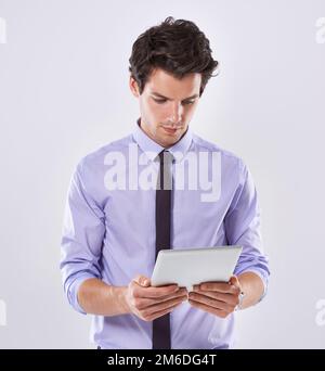 Business in a digital age. Studio shot of a handsome young businessman against a white background using a digital tablet. Stock Photo