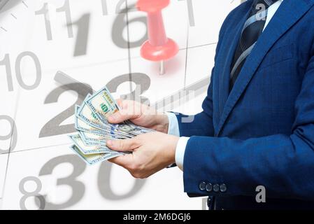 Businessman with money against background of calendar with a date stamp pin Stock Photo