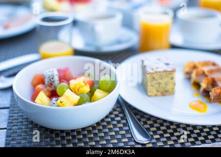 Fresh fruit salad, waffles, cake, coffee and juice served for breakfast at resort restaurant Stock Photo