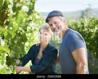 Theyre avid farmers. Happy mature couple checking the vines in their vineyard together. Stock Photo