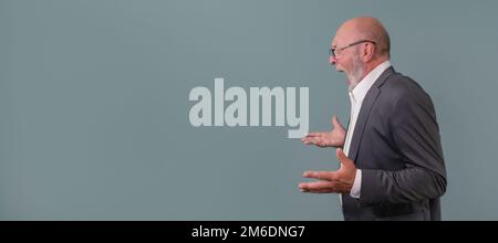 An angry elderly man in profile on a blue background. copy space. banner Stock Photo