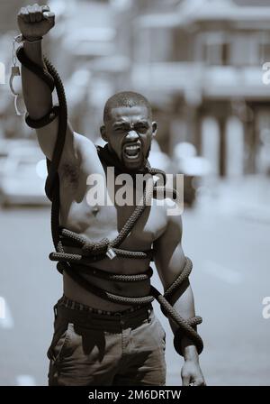 Protest, fist and man in rope and handcuffs in city protesting against discrimination, oppression or slavery and racism. Black lives matter, justice Stock Photo