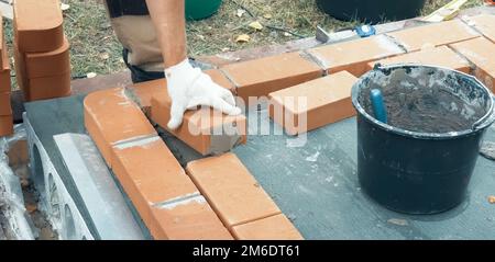 A man builds a brick wall. Brick put on the solution. Construction of brick house. Stock Photo