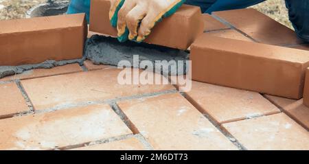 A man builds a brick wall. Brick put on the solution. Construction of brick house. Stock Photo