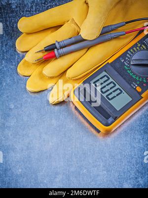 Digital electric tester safety gloves on metallic background. Stock Photo