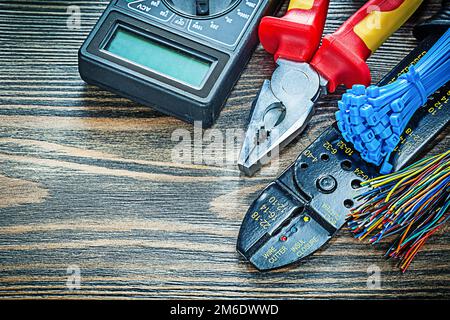 Electric tester wires cable ties bolt cutter pliers voltmeter on wooden board. Stock Photo