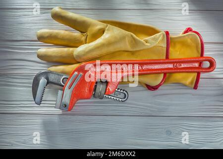 plumbers monkey wrench and yellow leather work gloves on vintage white painted wooden boards Stock Photo