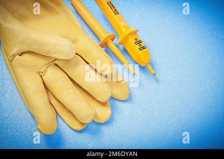 Top view of leather protective gloves electrical tester on blue background electricity concept. Stock Photo