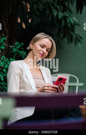 Woman using a mobile phone while sitting outdoors. Stock Photo