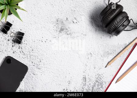 Top view of flat lay table composition with smartphone, pen, notepad and headphone on white gray background Stock Photo