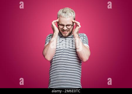 Young caucasian man wearing eyeglasses with headache rubbing his temple isolated over pink background. Overwork, exhausted, chronic fatigue, mental Stock Photo