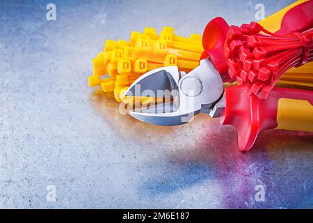 Composition of nippers tying cables on scratched metallic background. Stock Photo