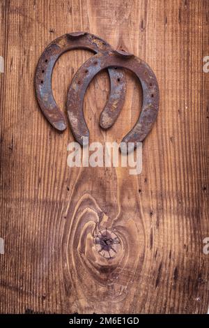 copyspace image two old cast iron metal western horse shoeing accessory horseshoes on antique wooden background happy concept vertical version Stock Photo