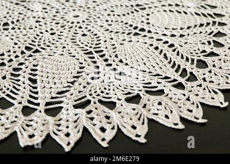 Part of a lace doily on a dark background. Handwork, a beautiful napkin. Stock Photo