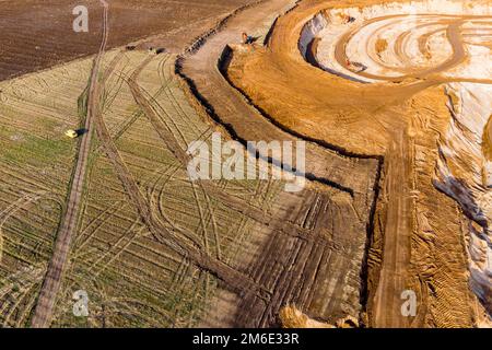 Aerial view of a growing sand pit at the expense of fields, overburden removal by excavators before sand extraction Stock Photo