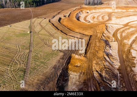 Aerial view of a growing sand pit at the expense of fields, overburden removal by excavators before sand extraction Stock Photo