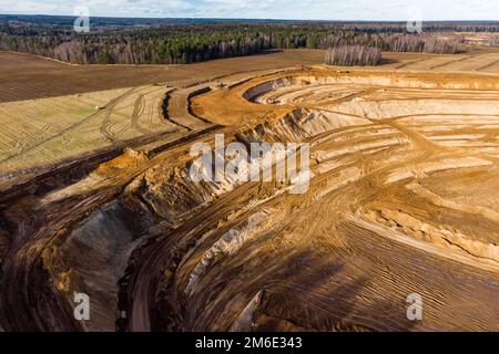 Aerial view of a growing sand pit at the expense of fields, overburden removal by excavators before sand extraction Stock Photo