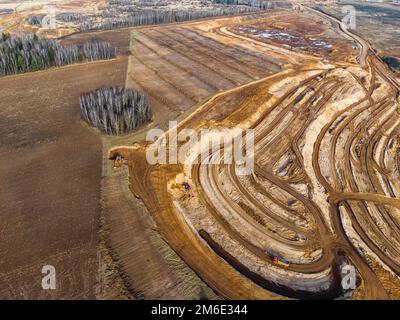 Aerial view of a growing sand pit at the expense of fields, overburden removal by excavators before sand extraction Stock Photo