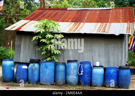 A row of blue plastic barrels in front of a garage building - an interesting still life composition Stock Photo