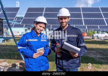 Maintenance engineer at solar farm hold drill machine and checklist stand smile to camera portrait Stock Photo