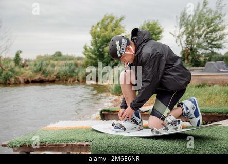 Bielawa, Polska. 03/06/2020 Wawa Wake. Athlete guy rides on a wakeboard. A man in sportswear swims on a lake in a wakeboard park Stock Photo