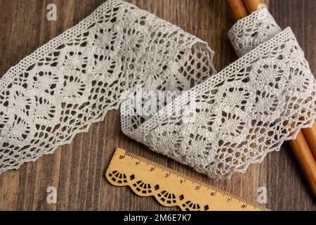 Knitted beige openwork linen ribbon tapes in rural style of rustics cotton eco natural on wood ground Stock Photo