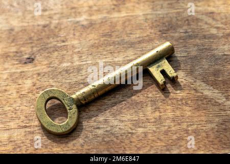 Old brass key on a wooden background Stock Photo