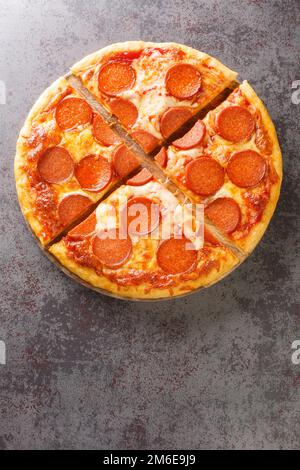 Hot homemade Pepperoni pizza ready to eat close-up on a wooden board on the table. Vertical top view from above Stock Photo